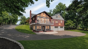 Ein zweistöckiges Haus mit Balkon, Garage und Auffahrt.