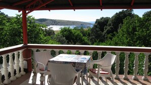 A covered outdoor area with a table and chairs, overlooking a scenic landscape with hills and a body of water. - Apartment in Lopar with Seaview, Terrace, Air condition, WIFI (4229-2) (Lopar)