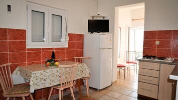 Enjoy meals in this cozy kitchen, featuring a dining table for two, a refrigerator, and a flat-screen TV.