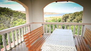 Varanda com um banco de madeira e uma mesa, com vista para uma paisagem deslumbrante com árvores e um corpo d'água.