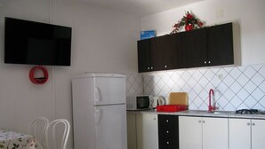 A compact kitchen with a refrigerator, microwave, sink, and a small dining area with a table and chairs. - Apartment in Lopar with Seaview, Loggia, Air condition, WIFI (4229-6) (Lopar)