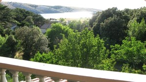 A balcony with a view of a lake, surrounded by trees and hills. - Apartment in Lopar with Seaview, Loggia, Air condition, WIFI (4229-6) (Lopar)