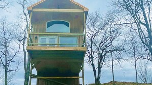 A wooden cabin with a balcony, surrounded by trees. - The "Hang-over"  Winery Treehouse (Weston)