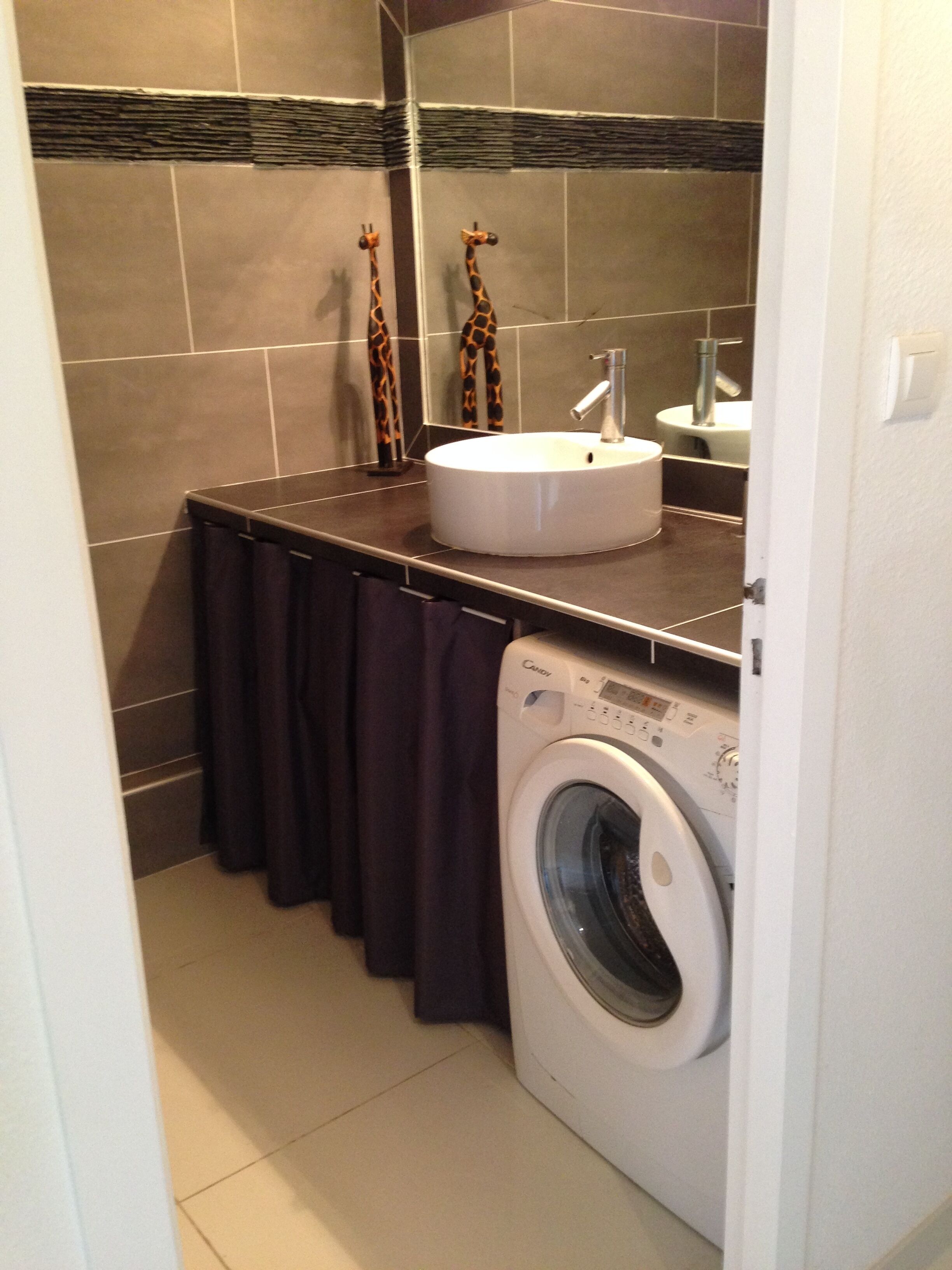 Un baño pequeño con lavadora, lavamanos y un perchero para toallas.