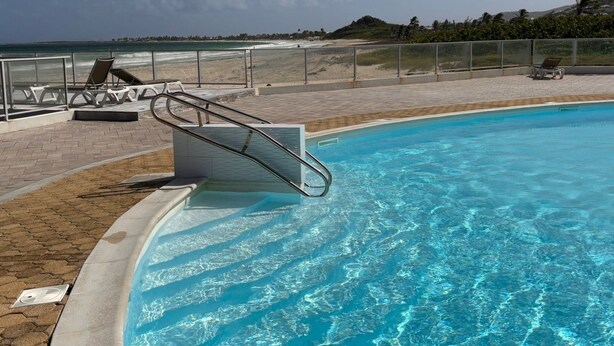 A swimming pool with a metal ladder, lounge chairs, and a view of the beach. - ♥Charming studio ♥♥ near Orient Bay beach (Saint Martin)