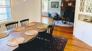 A dining area with a wooden table, woven placemats, black chairs, and a chandelier.
