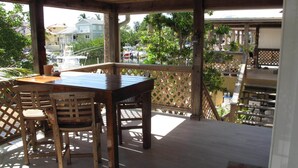 A wooden deck with a table and chairs, overlooking a marina and residential buildings. - Oceanside Key Largo Beauty w/Dock for 40' Boat (Key Largo)