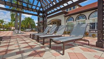 A covered outdoor area with sun loungers and a tiled floor.
