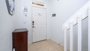 A narrow hallway with a white door, a small cabinet, and a white railing. - Recently renovated townhome near Theme Parks (Kissimmee)