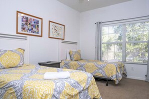 Une chambre d’hôtel avec deux lits, une table de chevet et une fenêtre avec des stores.