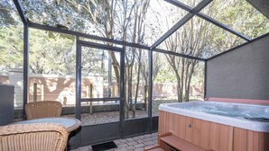 A covered patio area with a hot tub, wicker furniture, and a view of trees. - Recently renovated townhome near Theme Parks (Kissimmee)