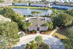 An aerial view of a residential area with a central building surrounded by trees and a body of water.