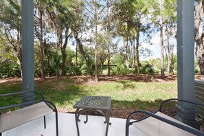 A covered patio with a table and chairs, surrounded by trees and a grassy area. - Emerald Island Townhome just 10min to Disney (Kissimmee)