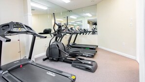 Un gimnasio con cintas de correr, elípticas y un espejo grande.
