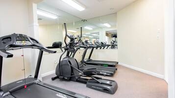 A gym with treadmills, elliptical machines, and a mirrored wall.