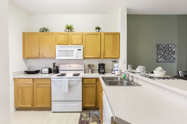 Una cocina moderna con armarios de madera, estufa blanca, microondas y cafetera.