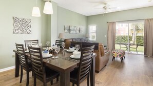 Comedor con una mesa de madera dispuesta para cuatro personas, un sofá y una pequeña mesa con sillas afuera.