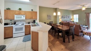 Una cocina moderna con armarios de madera, una estufa blanca y un comedor con mesa y sillas de madera.