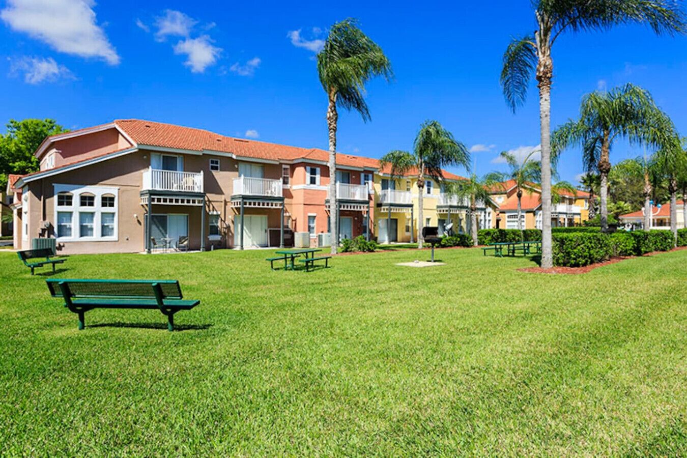 A residential area with houses, a grassy lawn, and benches.