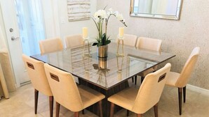 A dining area with a glass-top table surrounded by six beige chairs. - SpaciousTownhome 15 min to Disney Private Pool-BBQ (Kissimmee)