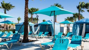 A poolside area with blue lounge chairs and umbrellas, palm trees, and a tiled floor. - SpaciousTownhome 15 min to Disney Private Pool-BBQ (Kissimmee)