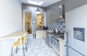 A modern kitchen with a dining table and chairs, a water dispenser, and a stove.