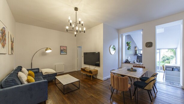 Un salon moderne comprenant un canapé, une table basse, un téléviseur et un coin repas avec des chaises.