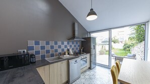 Une cuisine moderne équipée d’un four à micro-ondes, d’une cuisinière et d’un lave-vaisselle, dotée de grandes fenêtres et d’un sol à motifs.