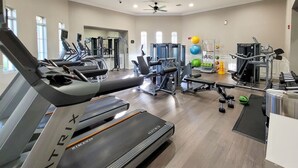 A modern gym with treadmills, weight machines, and free weights.