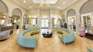 A spacious lobby with a central seating area, a chandelier, and a reception desk.