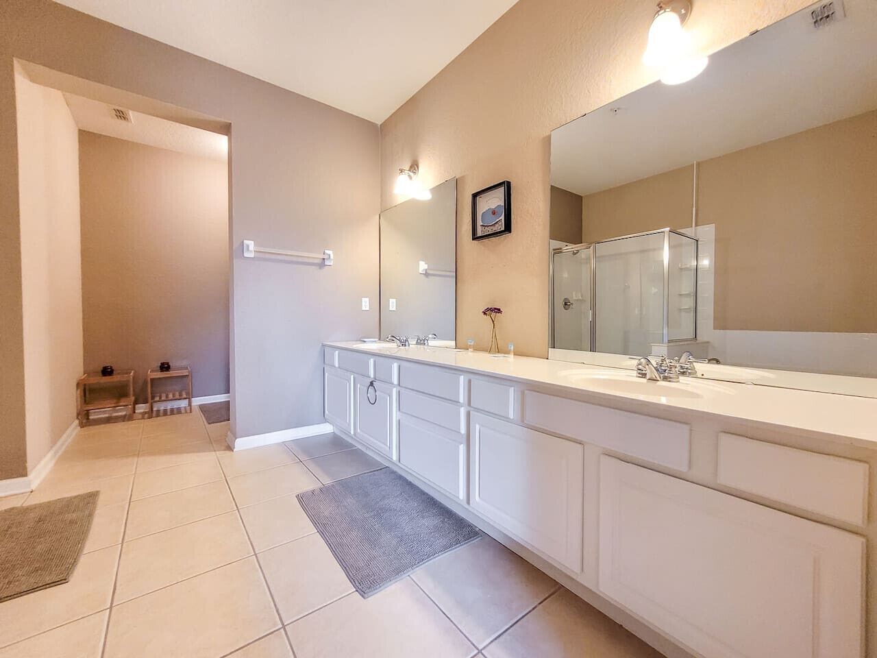 A modern bathroom with a long vanity, a large mirror, and a shower area.