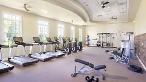 Een fitnessruimte met loopbanden, elliptische trainers en gewichten.