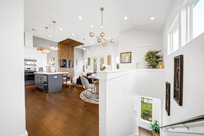 Cozinha ampla com eletrodomésticos modernos, área de jantar com mesa redonda e escada que dá acesso a um andar superior.