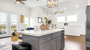 A modern kitchen with a large island, grey cabinets, and a stainless steel refrigerator. - Spacious 3BR Houston Escape near Downtown with Spa (Houston)
