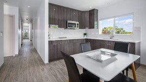 A modern kitchen with dark wood cabinets, a white countertop, and a large window. - The Makai Manor - Beautiful Newly Built Spacious Home (Honolulu)