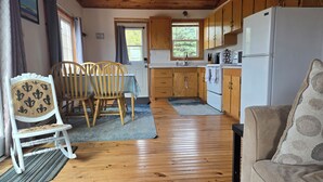 Una cocina compacta con armarios de madera, un refrigerador blanco y una zona de comedor con mesa y sillas.