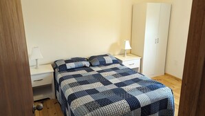 Un dormitorio con una cama, dos mesitas de noche, un armario y una puerta.