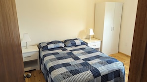 Ein Schlafzimmer mit einem Bett, zwei Nachttischen, einem Schrank und einer Tür.