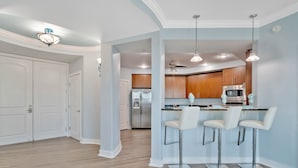 Una cocina moderna con una isla central, taburetes de bar y electrodomésticos de acero inoxidable.
