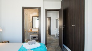 A hotel room with a bed, a nightstand, a lamp, a bathroom with a sink and mirror, and a dark wooden wardrobe. - Planta Baja - Villa Arosa (Playa Blanca)