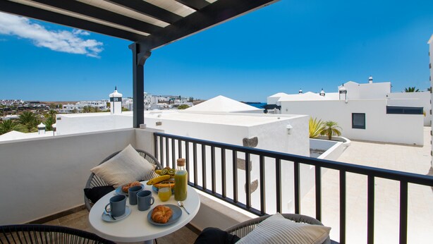 A balcony with a table set for breakfast, overlooking a coastal cityscape. - Planta Baja - Villa Arosa (Playa Blanca)