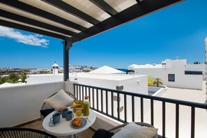 Un balcon avec une table préparée pour le petit-déjeuner, offrant une vue sur le paysage urbain de la côte.