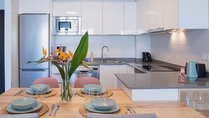 A modern kitchen with white cabinets, stainless steel appliances, and a central island. - Planta Baja - Villa Arosa (Playa Blanca)