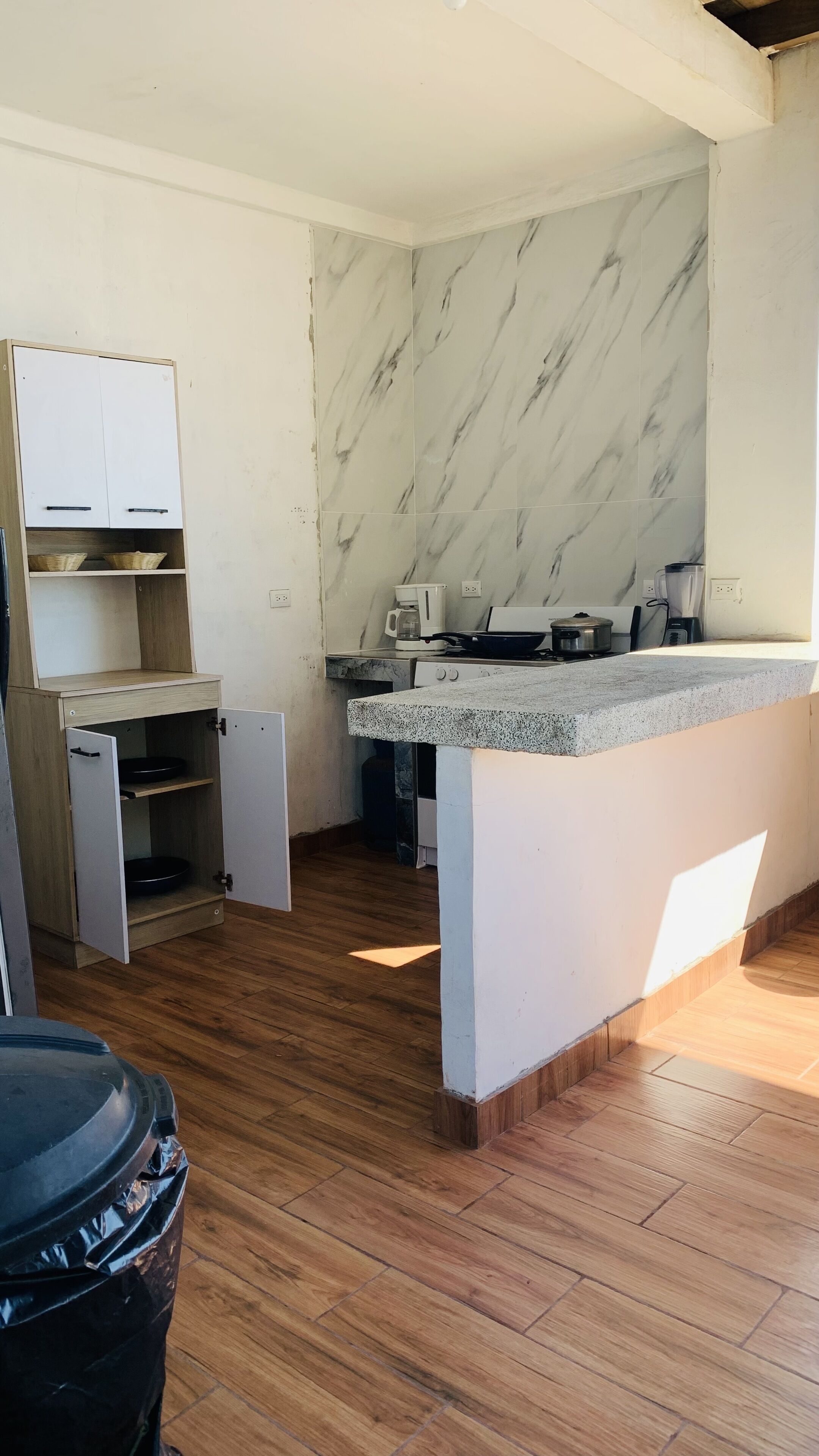 Una cucina compatta con zoccolo in marmo, mobili in legno e piano di lavoro in granito.