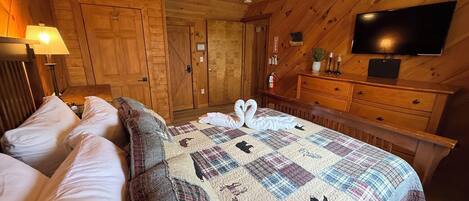 A wooden-paneled room with a bed, a television, and a dresser.