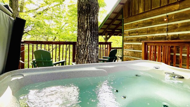 Ein Whirlpoolbereich mit Holzterrasse, umgeben von Bäumen und einem überdachten Sitzbereich.