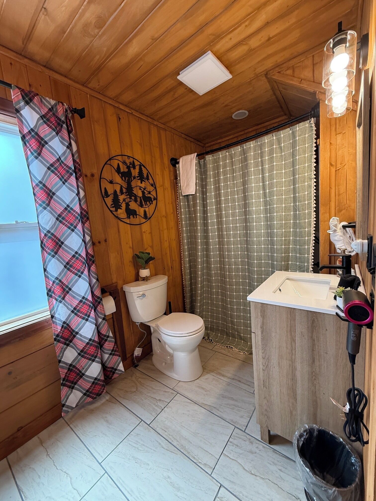 Ein Badezimmer mit Holzwandverkleidung, Toilette, Waschbecken und Duschvorhang.
