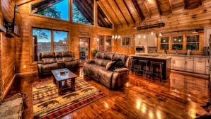 A cozy log cabin interior with a living room, sofa, and kitchen area. - Stress Free Summit - Mountain Views | Hot Tub | Outdoor Fireplace | Gas Grill (Blue Ridge)