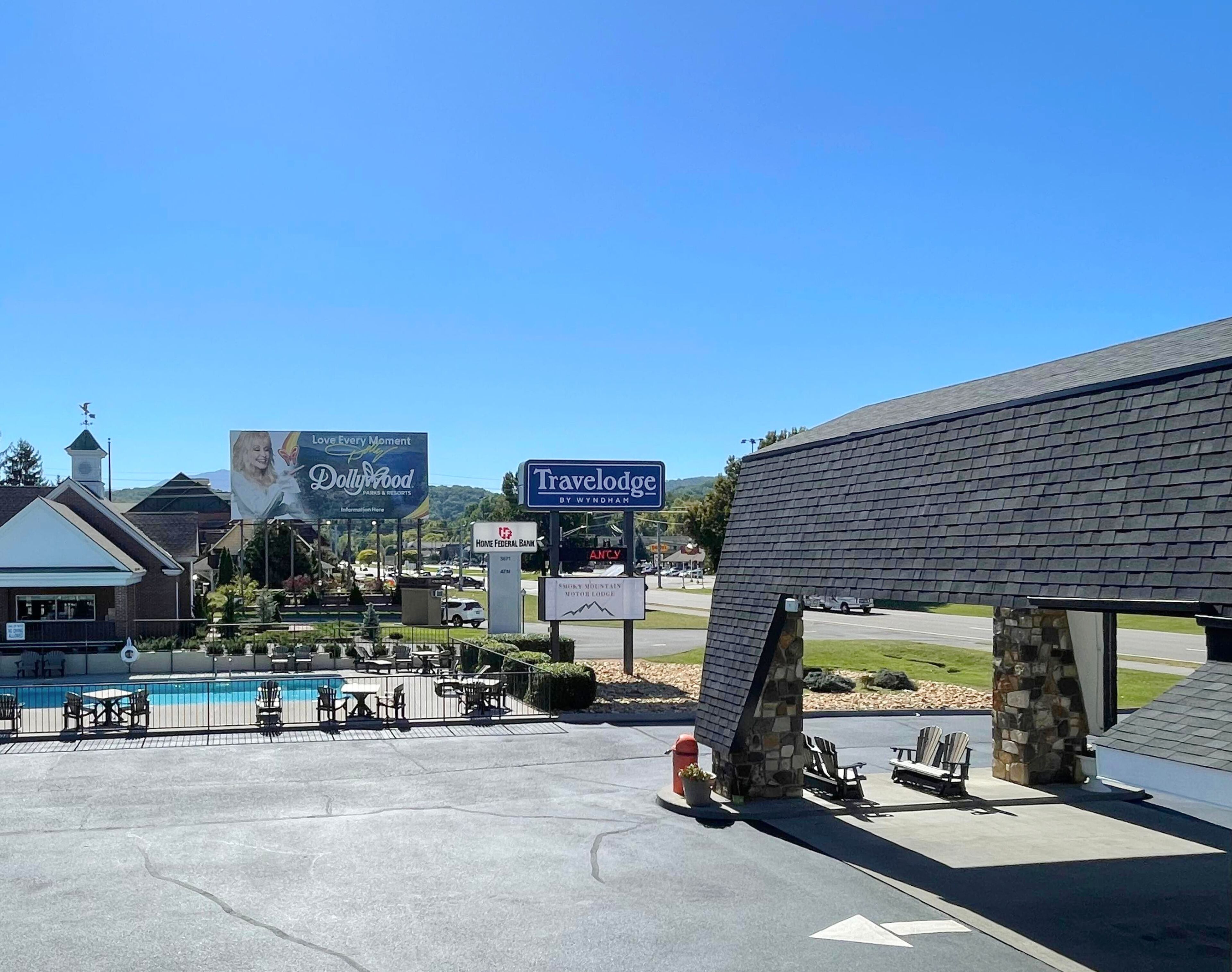 Un hotel Travelodge by Wyndham con área de piscina, mobiliario exterior y una estructura de piedra.