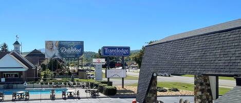 A Travelodge by Wyndham with a pool area, outdoor seating, and a stone structure.